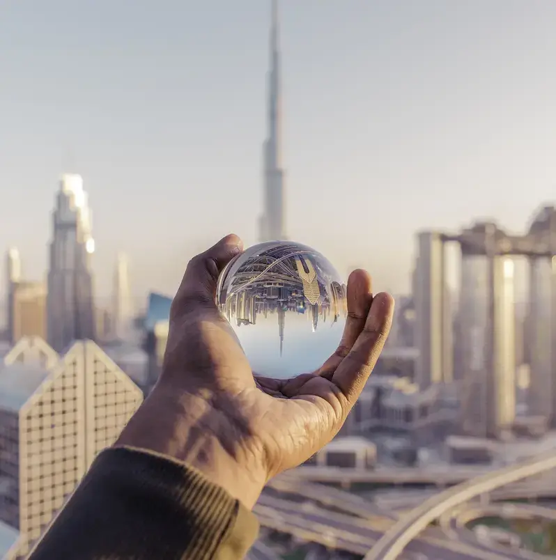 closeup shot male hand holding crystal ball with reflection city